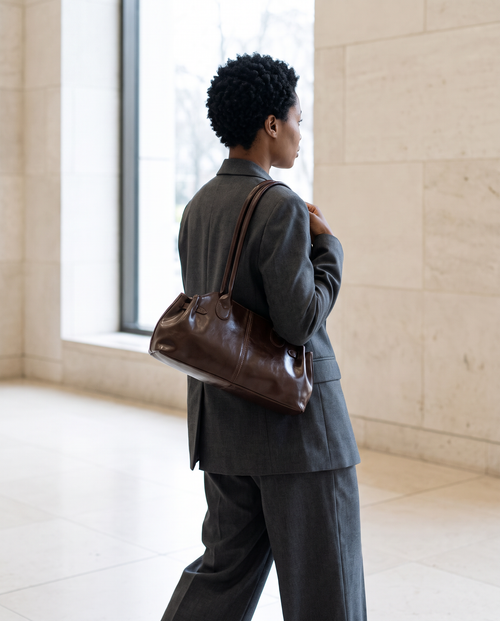 Mujer con el bolso de hombro Aura chocolate y traje gris