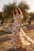 Woman wearing the Sol floral chiffon maxi dress with puff sleeves and a tiered skirt in a sunlit garden